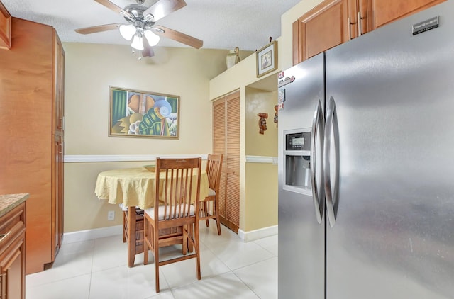 kitchen featuring ceiling fan, stainless steel refrigerator with ice dispenser, a textured ceiling, and light tile patterned floors