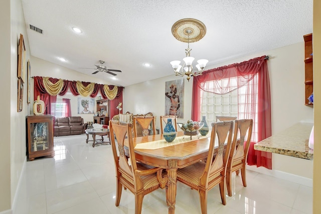 tiled dining room with a textured ceiling and ceiling fan with notable chandelier