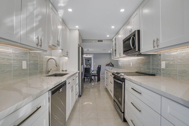 kitchen featuring decorative backsplash, stainless steel appliances, white cabinetry, and sink