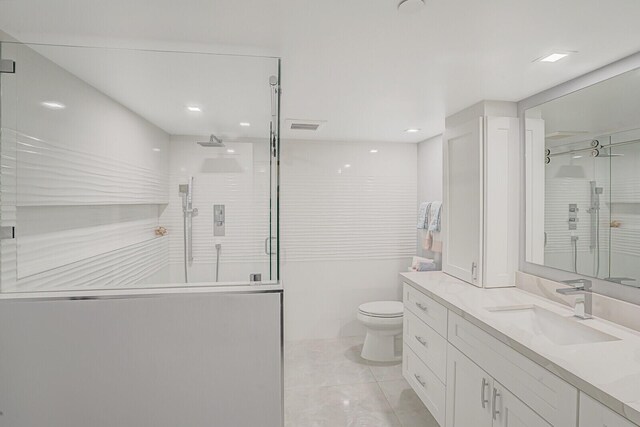 bathroom featuring tile patterned floors, toilet, a tile shower, and vanity