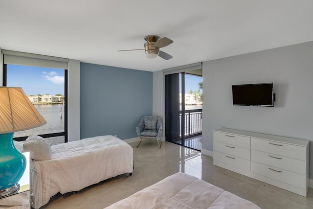 bedroom featuring access to outside, multiple windows, ceiling fan, and a water view