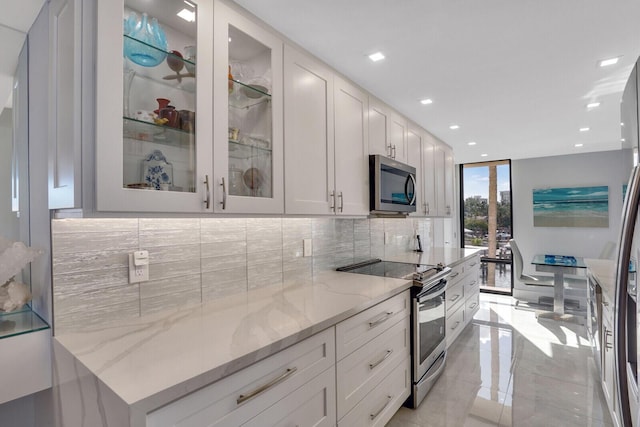 kitchen featuring decorative backsplash, light stone countertops, white cabinetry, and stainless steel appliances