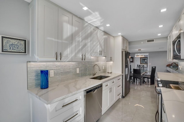 kitchen featuring light stone countertops, appliances with stainless steel finishes, tasteful backsplash, sink, and white cabinets