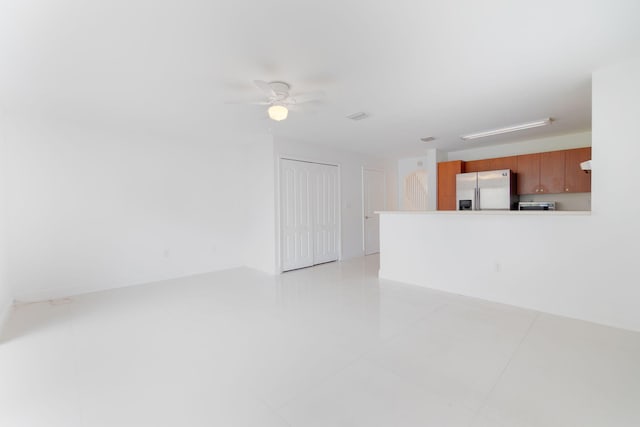 unfurnished living room featuring light tile patterned floors and ceiling fan