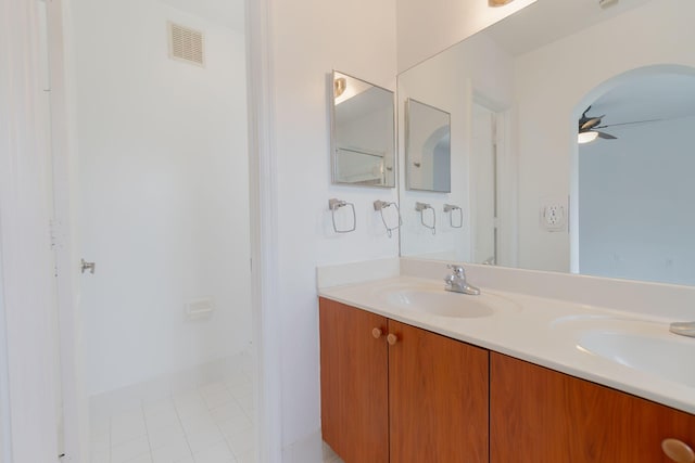 full bath with double vanity, a ceiling fan, visible vents, and a sink