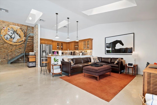 living room featuring lofted ceiling with skylight and brick wall