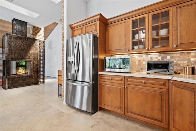 kitchen featuring appliances with stainless steel finishes, tasteful backsplash, and light stone counters