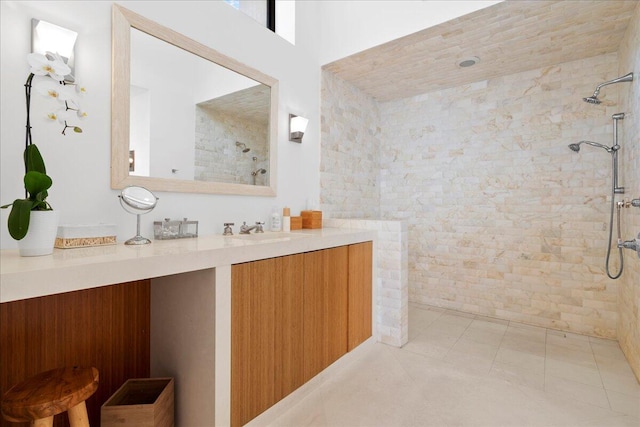 bathroom with tile patterned flooring, vanity, and tiled shower