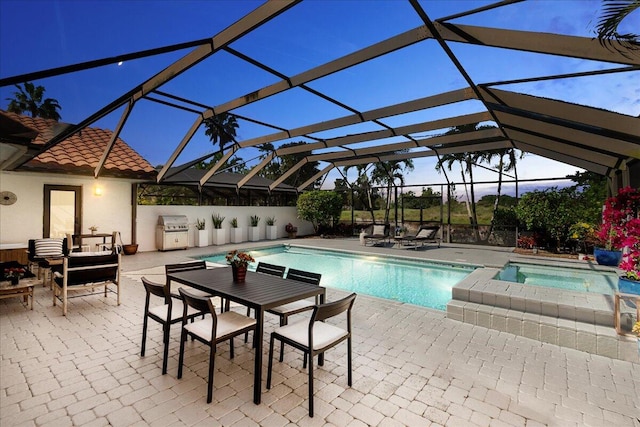 pool at dusk featuring area for grilling, a patio area, and glass enclosure