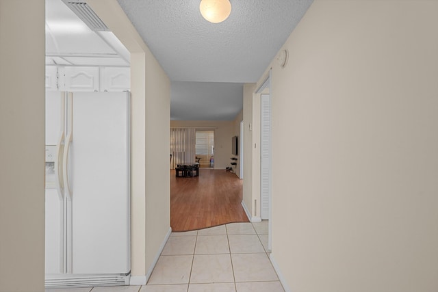 corridor featuring light tile patterned floors and a textured ceiling