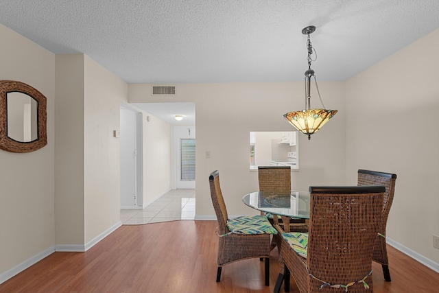 dining space featuring a textured ceiling and light wood-type flooring