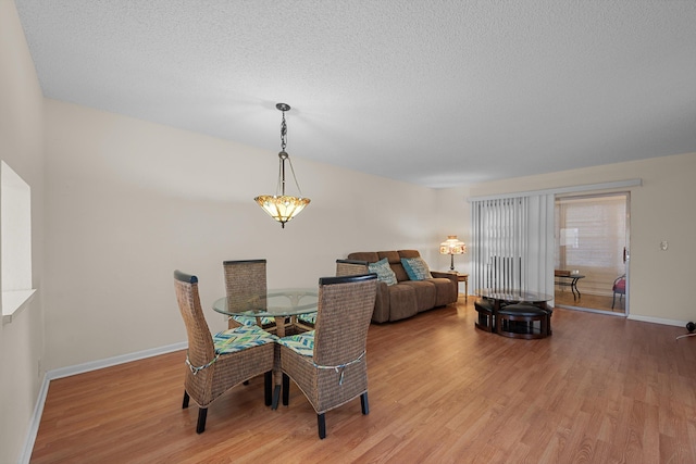 dining area featuring light wood-type flooring and a textured ceiling