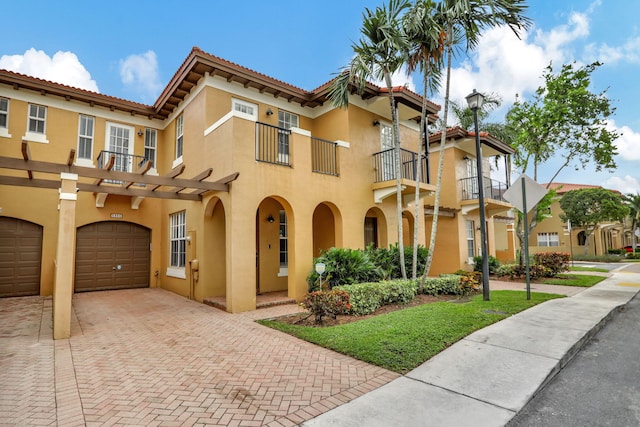 mediterranean / spanish-style home featuring a garage and a balcony