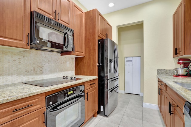 kitchen featuring black appliances, light stone countertops, light tile patterned floors, and tasteful backsplash