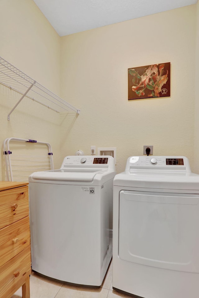 clothes washing area featuring washing machine and dryer and light tile patterned floors