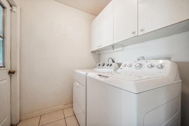 washroom featuring light tile patterned flooring, washer and dryer, a textured ceiling, and cabinets