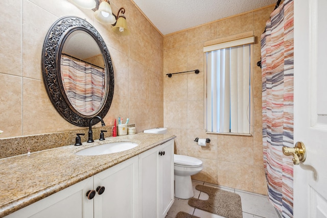 bathroom with a textured ceiling, tile walls, toilet, vanity, and tile patterned floors