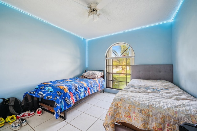 bedroom with ceiling fan, tile patterned floors, and a textured ceiling