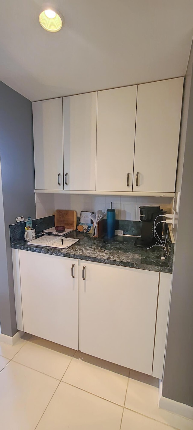 kitchen with dark stone countertops, light tile patterned flooring, and white cabinets