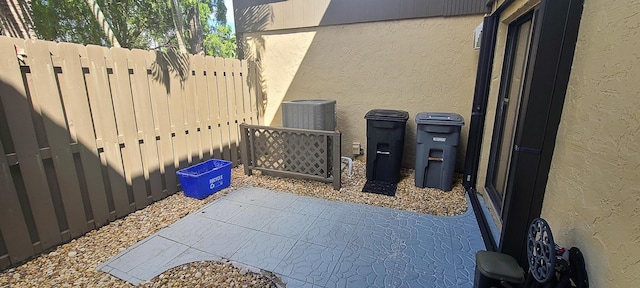 exterior details featuring central AC unit, stucco siding, and fence