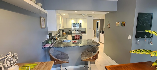 kitchen featuring a peninsula, dark countertops, white cabinetry, a ceiling fan, and appliances with stainless steel finishes