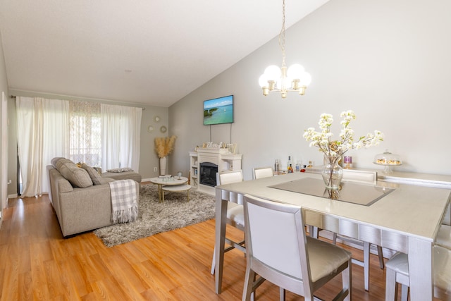 dining area featuring high vaulted ceiling, a chandelier, and light wood-type flooring