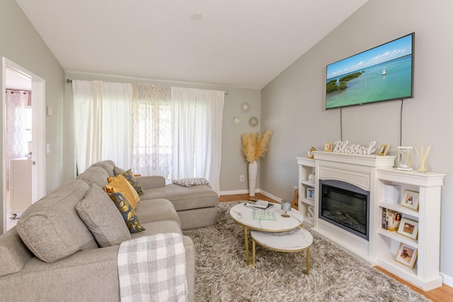 living room featuring hardwood / wood-style floors, vaulted ceiling, and a textured ceiling