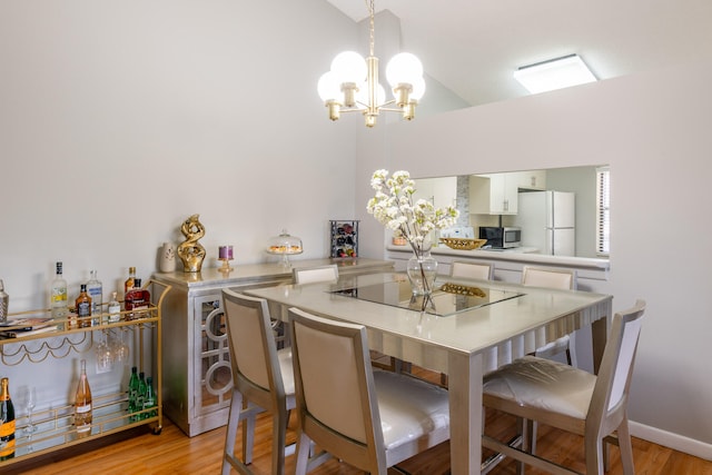 dining room featuring a notable chandelier, high vaulted ceiling, and light wood-type flooring