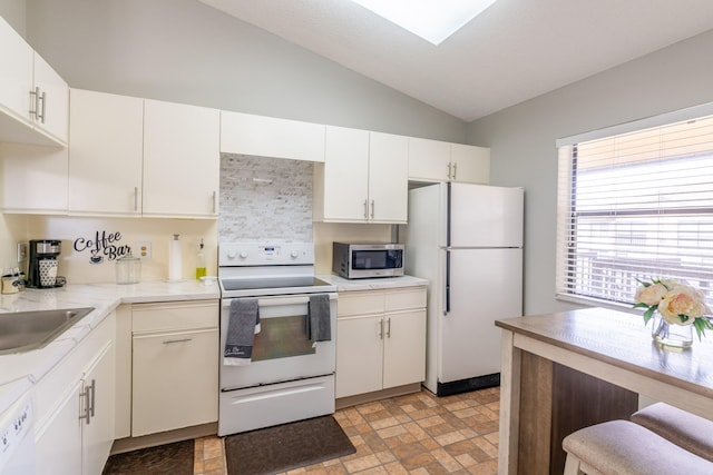 kitchen with sink, vaulted ceiling, white appliances, and white cabinets