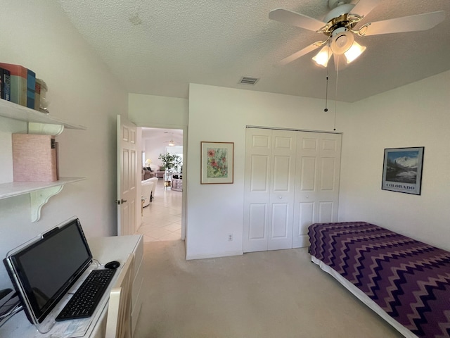 carpeted bedroom with a closet, a textured ceiling, and ceiling fan