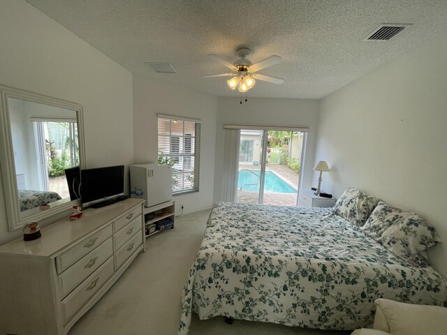 bedroom featuring ceiling fan, light carpet, a textured ceiling, and access to exterior