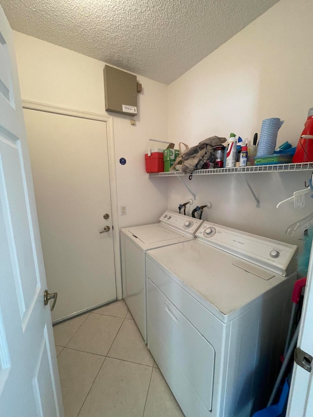 washroom featuring a textured ceiling, light tile patterned flooring, and washing machine and dryer