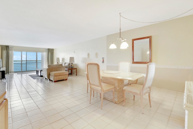 dining area featuring a chandelier, a water view, and light tile patterned floors