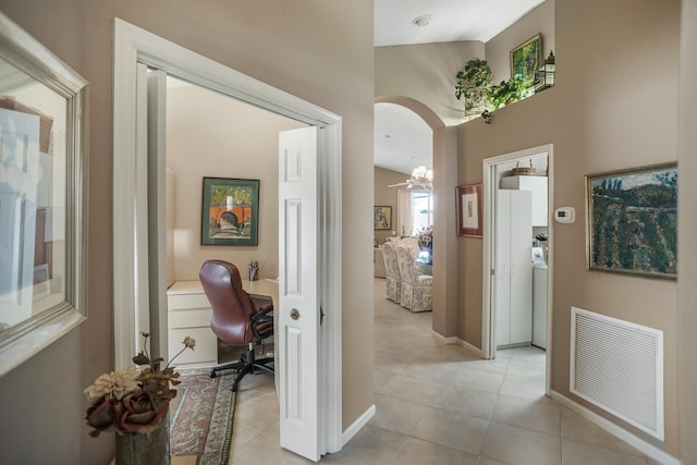 hallway featuring lofted ceiling, light tile patterned flooring, and washer / clothes dryer