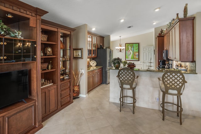 kitchen with a kitchen bar, kitchen peninsula, stainless steel appliances, decorative light fixtures, and an inviting chandelier