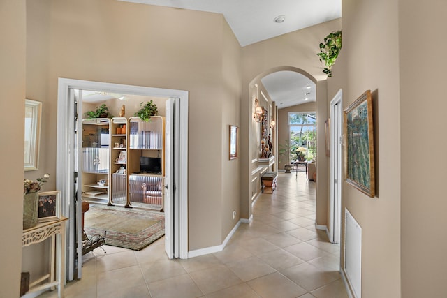 corridor featuring high vaulted ceiling and light tile patterned floors