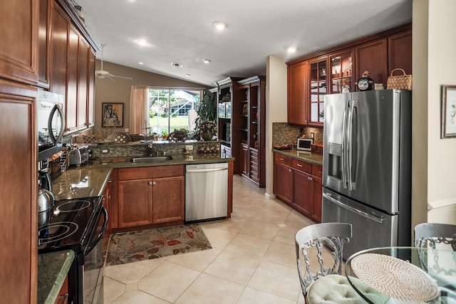 kitchen featuring appliances with stainless steel finishes, light tile patterned flooring, kitchen peninsula, vaulted ceiling, and decorative backsplash