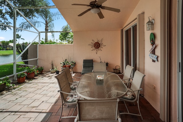 view of patio with a water view, ceiling fan, and a lanai