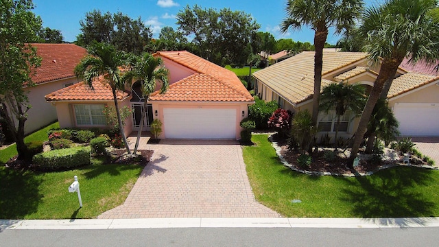 mediterranean / spanish home featuring a front yard and a garage