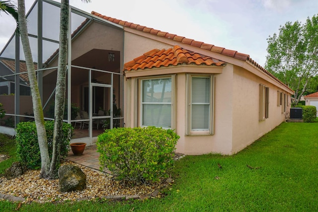 view of home's exterior with a yard, a patio, central AC unit, and a lanai