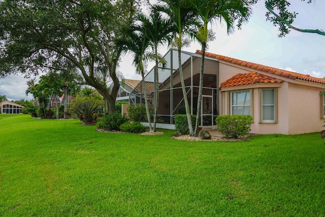 back of house featuring a yard and glass enclosure