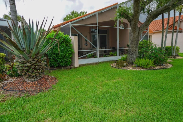 rear view of property with a lawn and a lanai