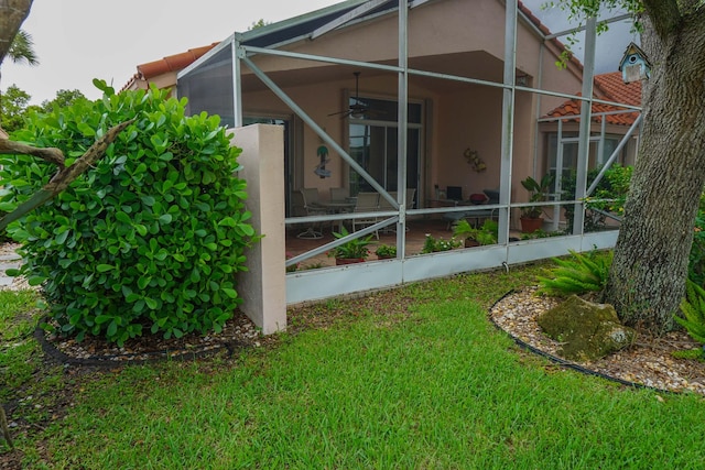 view of side of property featuring a lanai and a lawn