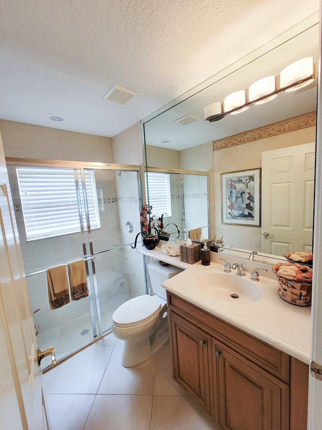 bathroom featuring a shower with door, a textured ceiling, toilet, vanity, and tile patterned flooring