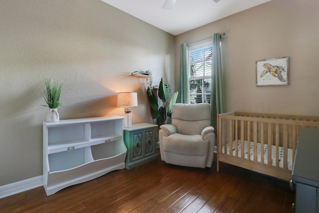 bedroom with ceiling fan, dark hardwood / wood-style floors, and a crib