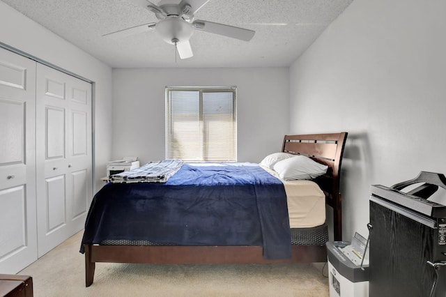 carpeted bedroom featuring a closet, a textured ceiling, and ceiling fan