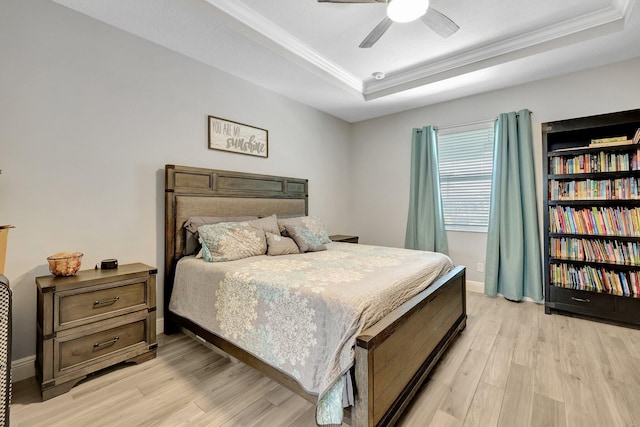 bedroom featuring ceiling fan, a raised ceiling, light hardwood / wood-style flooring, and crown molding