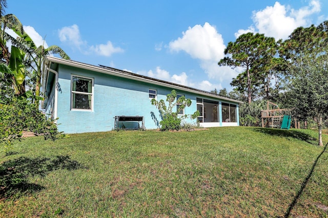 back of house featuring a sunroom and a lawn