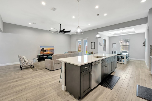 kitchen with dishwasher, light hardwood / wood-style flooring, a center island with sink, sink, and decorative light fixtures