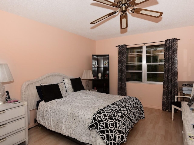 bedroom with light hardwood / wood-style flooring, a textured ceiling, and ceiling fan